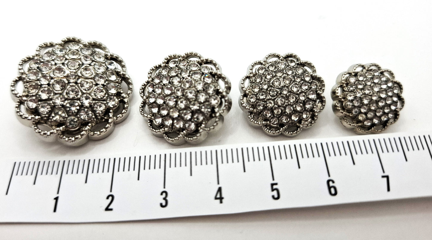 Four decorative buttons with rhinestones on a ruler for scale.